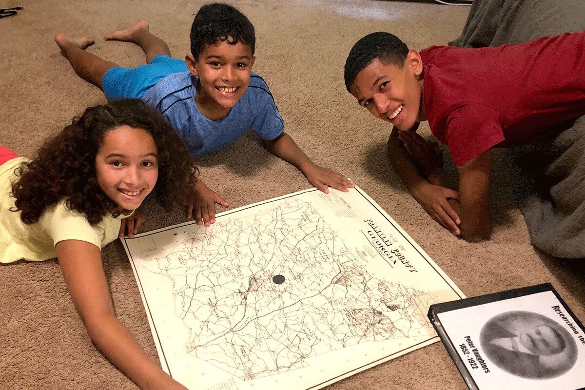 The author's children with a map and a book of their family history.