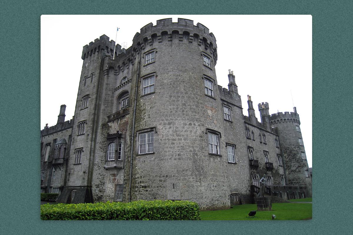 A grey-colored Kilkenny Castle in Kilkenny Ireland, surrounded by greenery