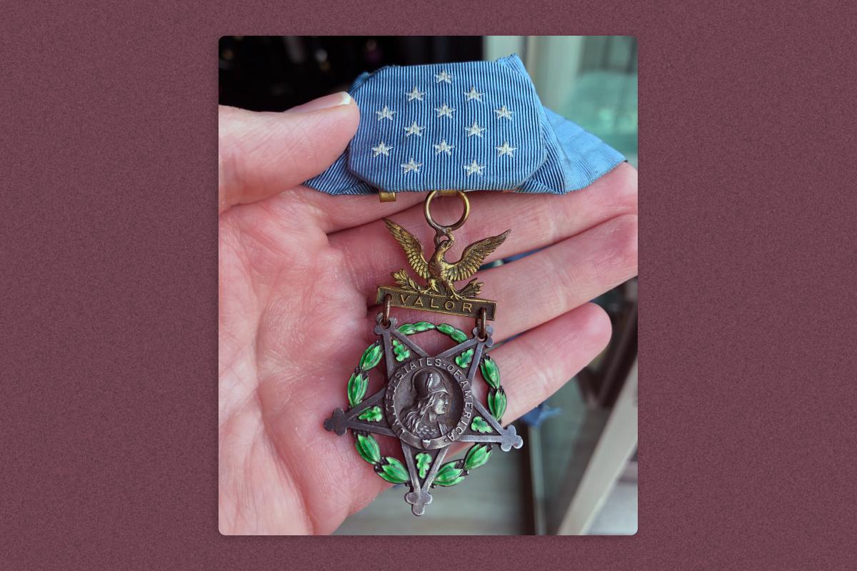 A hand holding Michael Valente's Medal of Honor